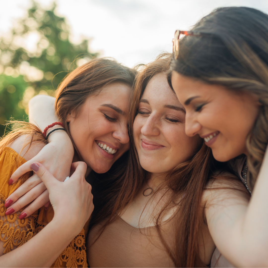 Three people hugging each other and smiling.