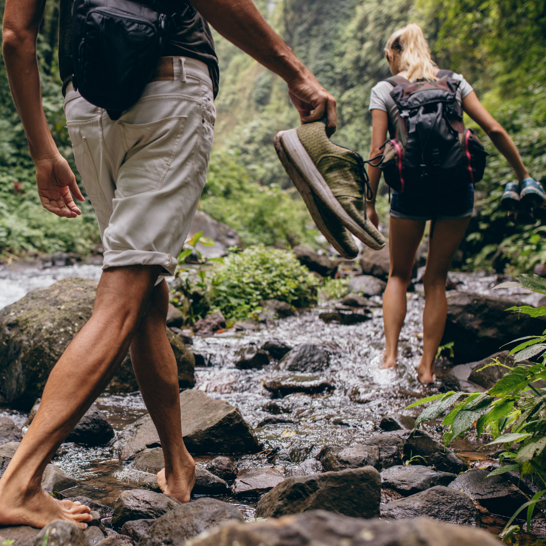 Two people walking barefoot in the woods.