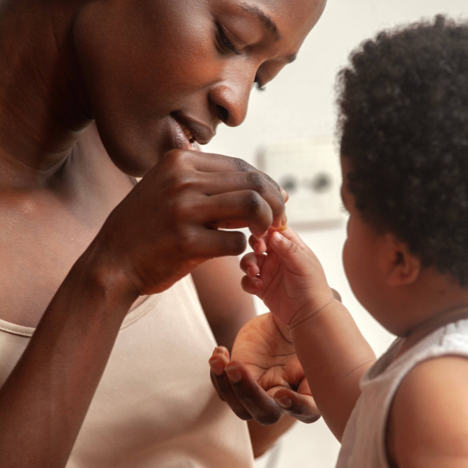 Woman gently feeding a baby in a cozy indoor setting. Both display a calm and tender interaction. Soft lighting enhances the warmth.